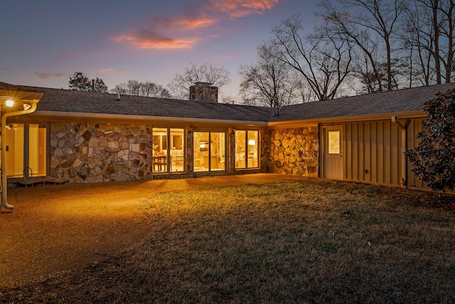 back house at dusk with a lawn