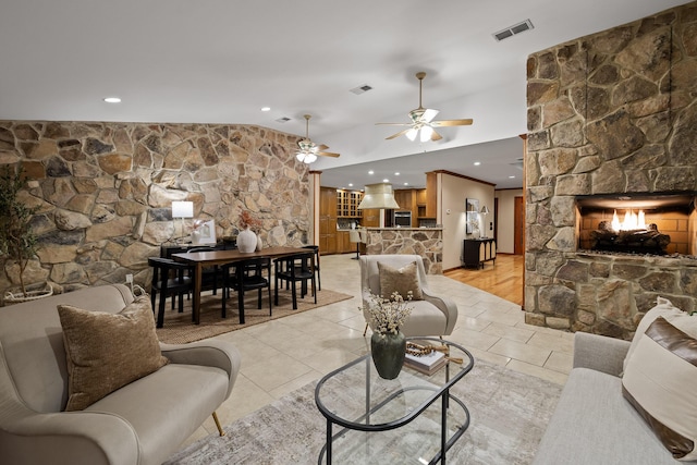 living room with ceiling fan, lofted ceiling, a stone fireplace, and light tile patterned floors