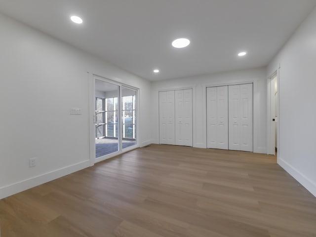 unfurnished bedroom with access to outside, light hardwood / wood-style floors, and multiple closets