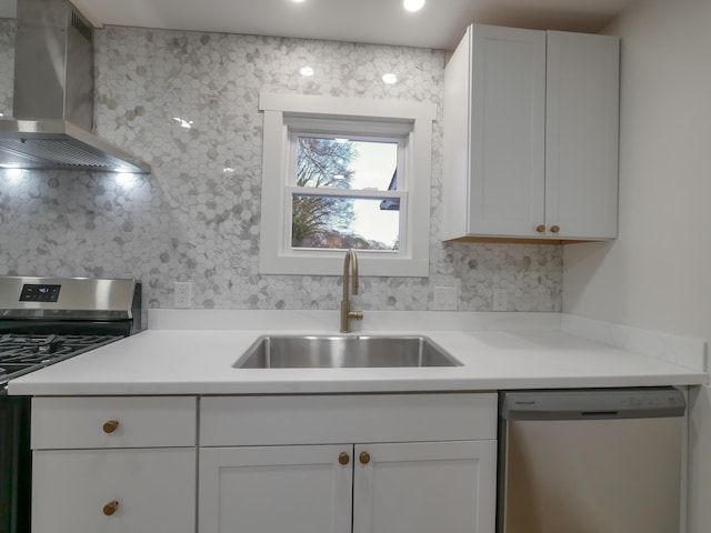 kitchen featuring appliances with stainless steel finishes, wall chimney exhaust hood, white cabinets, backsplash, and sink