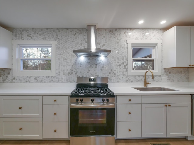 kitchen with sink, white cabinets, wall chimney range hood, and stainless steel gas range oven