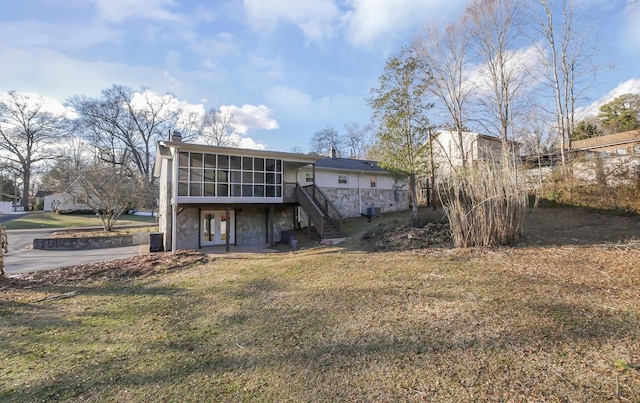 rear view of property featuring a yard and a sunroom