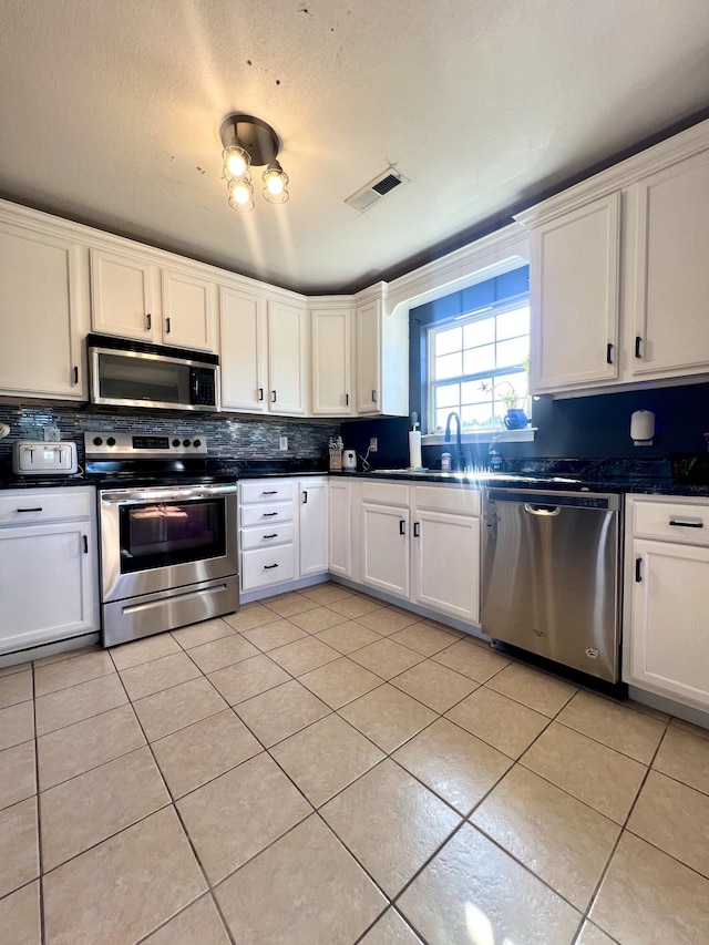 kitchen featuring white cabinets, sink, light tile patterned flooring, and appliances with stainless steel finishes