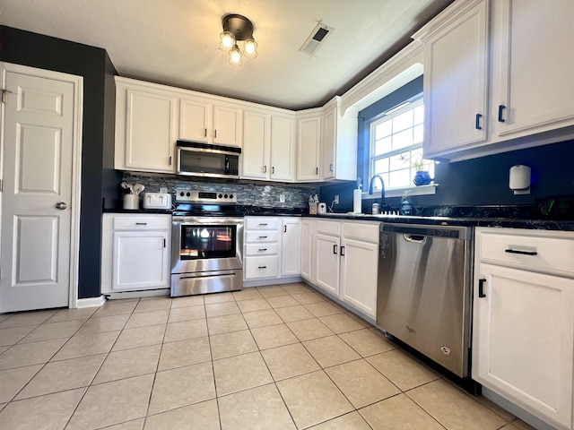 kitchen featuring sink, light tile patterned floors, appliances with stainless steel finishes, tasteful backsplash, and white cabinetry