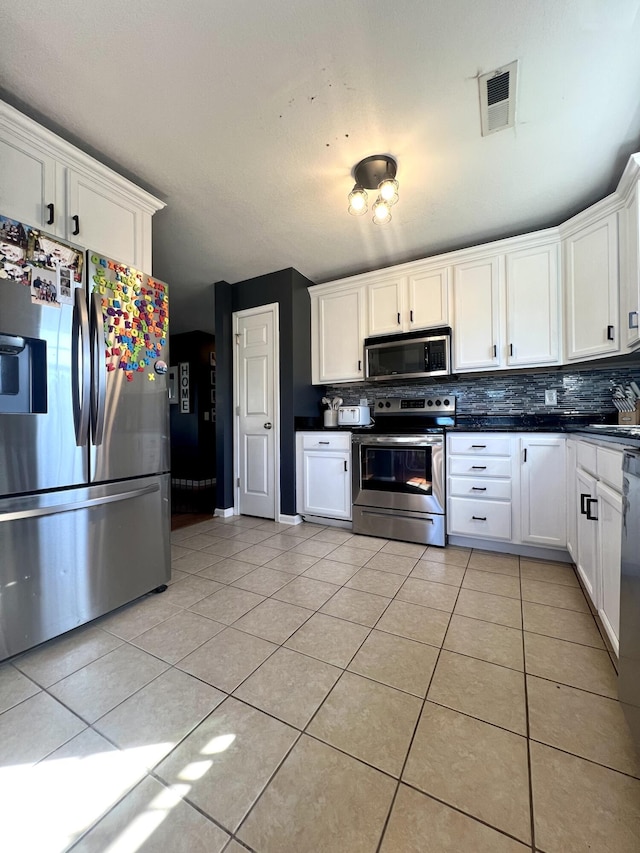 kitchen with white cabinetry, light tile patterned floors, stainless steel appliances, and tasteful backsplash