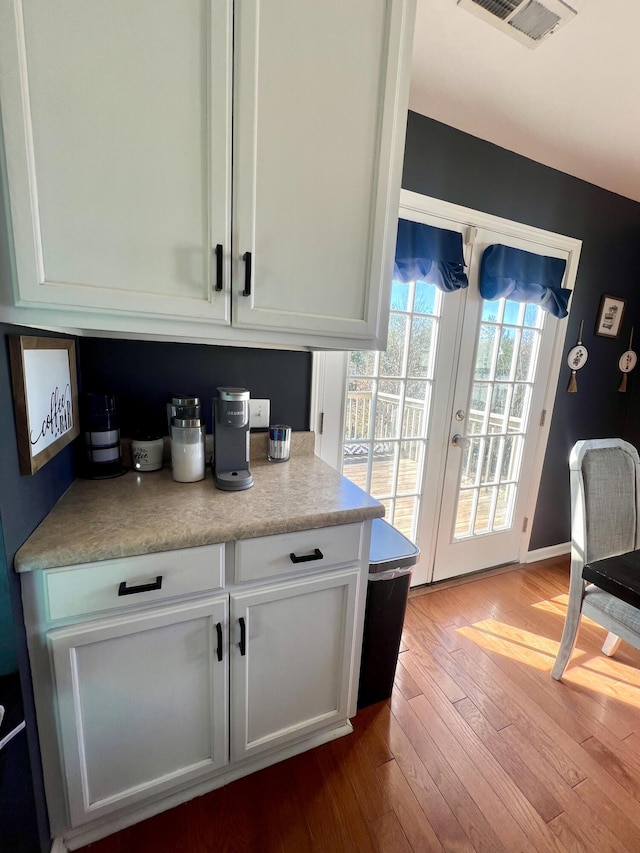 bar with french doors, white cabinets, and light hardwood / wood-style floors