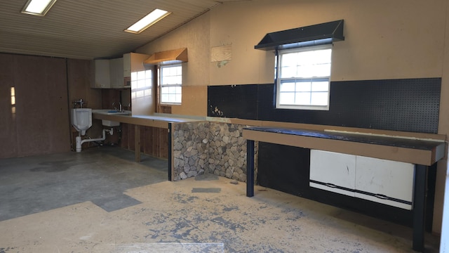 kitchen with lofted ceiling, a wealth of natural light, and concrete flooring