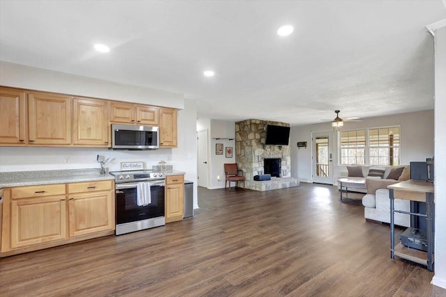 kitchen with a stone fireplace, light brown cabinetry, dark hardwood / wood-style flooring, ceiling fan, and stainless steel appliances