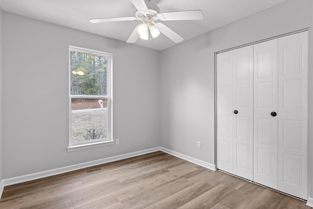 unfurnished bedroom with ceiling fan, light hardwood / wood-style flooring, and a closet