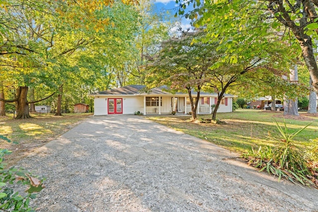 view of front of property with a porch, a front yard, and french doors