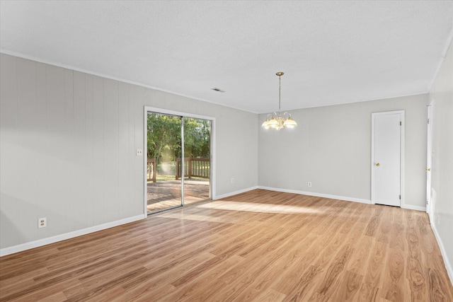 spare room with light wood-type flooring, a textured ceiling, and a notable chandelier