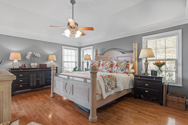 bedroom featuring hardwood / wood-style flooring, ceiling fan, ornamental molding, and multiple windows