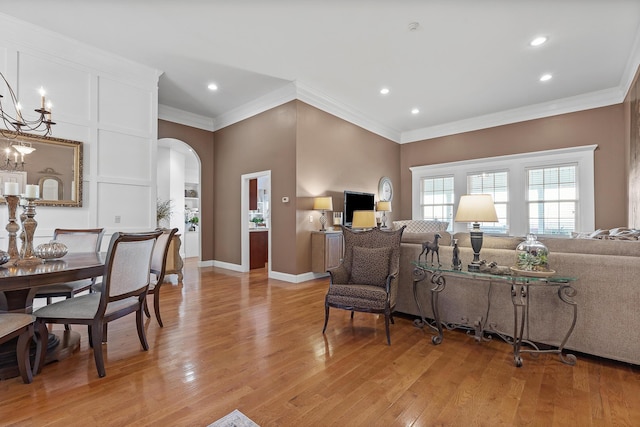 living room with light hardwood / wood-style floors, an inviting chandelier, and ornamental molding