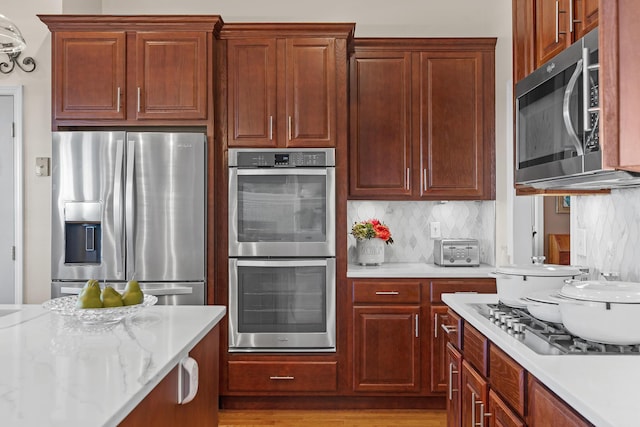 kitchen featuring light stone countertops, backsplash, and appliances with stainless steel finishes