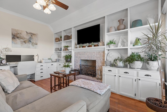 living room with hardwood / wood-style floors, a brick fireplace, ceiling fan, and ornamental molding