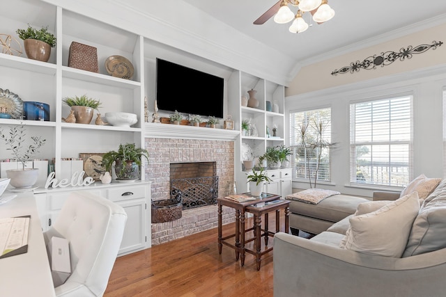 living room featuring vaulted ceiling, ceiling fan, built in features, a fireplace, and light hardwood / wood-style floors