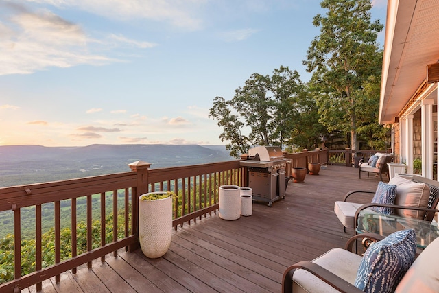 deck at dusk with a mountain view and area for grilling