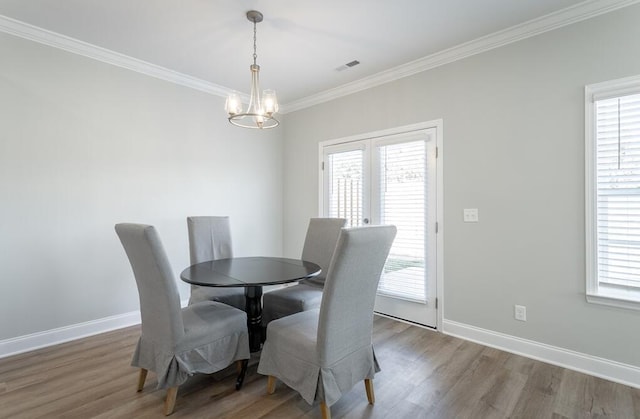 dining area featuring hardwood / wood-style flooring, a healthy amount of sunlight, and an inviting chandelier