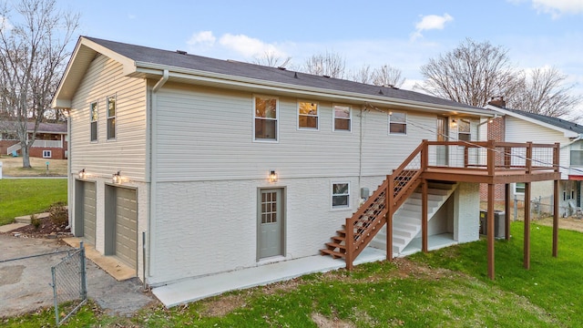 back of property with a garage, a deck, central air condition unit, and a lawn