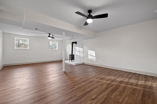 unfurnished living room with ceiling fan, dark hardwood / wood-style flooring, and a wood stove