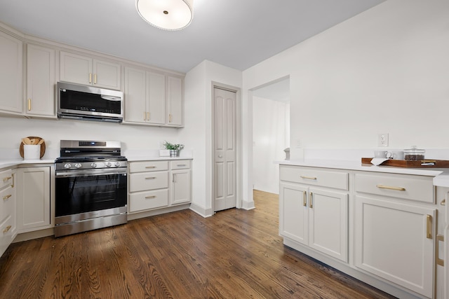 kitchen with white cabinetry, stainless steel appliances, and dark hardwood / wood-style floors