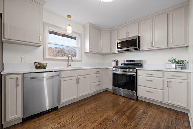 kitchen with decorative light fixtures, stainless steel appliances, dark hardwood / wood-style flooring, white cabinets, and sink