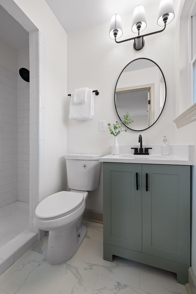 bathroom with vanity, toilet, and tiled shower