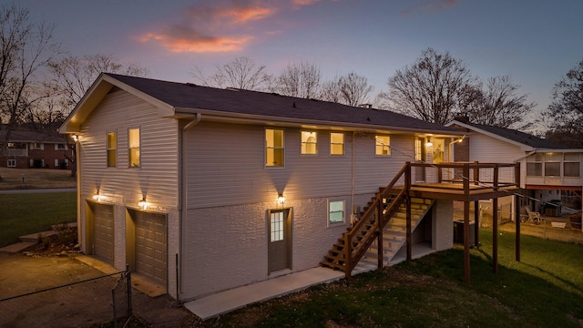 back house at dusk featuring a garage and a wooden deck