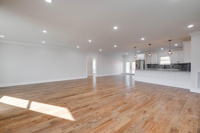 unfurnished living room featuring crown molding and light hardwood / wood-style floors