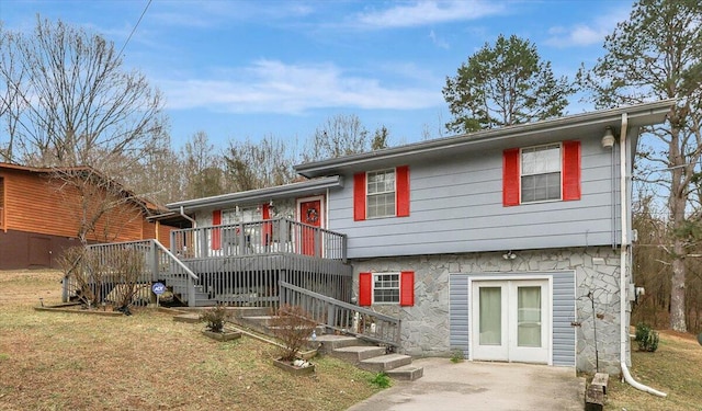 rear view of property featuring a wooden deck, a lawn, and french doors