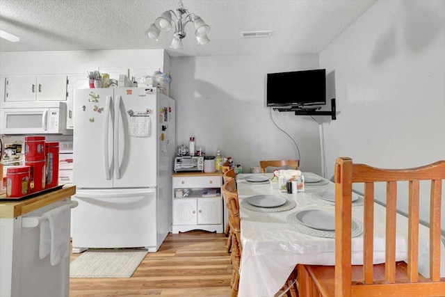 kitchen with white cabinetry, white appliances, a textured ceiling, and light wood-type flooring