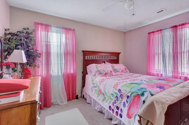 bedroom featuring light carpet, a textured ceiling, and ceiling fan