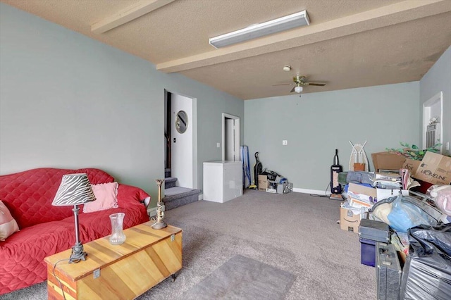 living room with beamed ceiling, ceiling fan, carpet flooring, and a textured ceiling