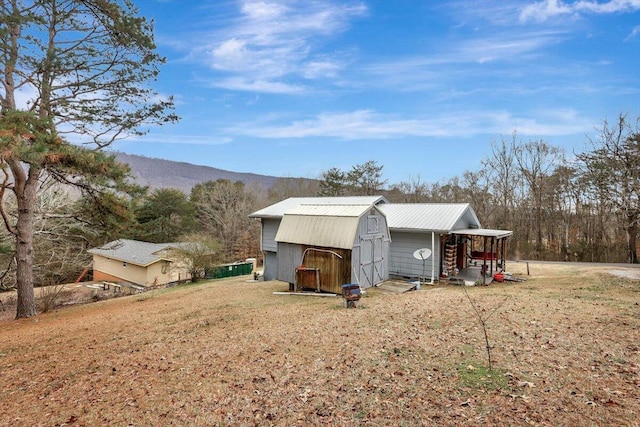 exterior space featuring a mountain view, a yard, and an outdoor structure