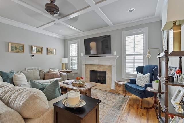 living room with hardwood / wood-style floors, beam ceiling, crown molding, coffered ceiling, and a tiled fireplace