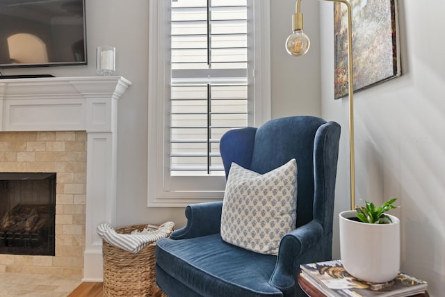 sitting room featuring wood-type flooring, a tile fireplace, and ornamental molding