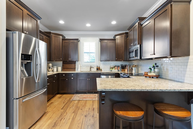 kitchen with a kitchen breakfast bar, ornamental molding, stainless steel appliances, and tasteful backsplash