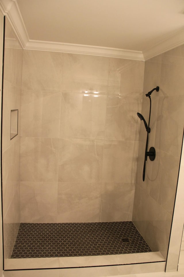 bathroom with ornamental molding and tiled shower