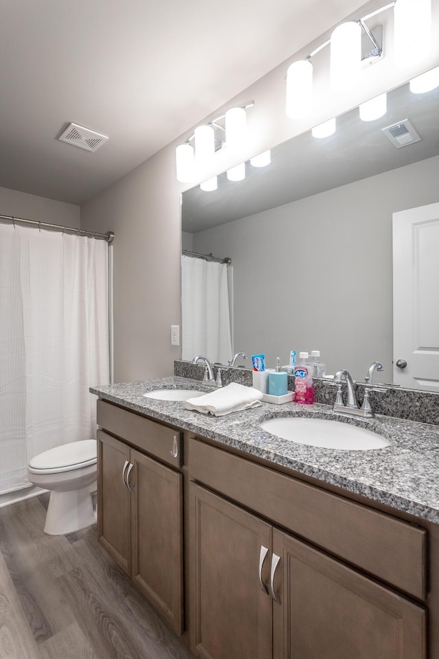 bathroom with toilet, vanity, and hardwood / wood-style floors