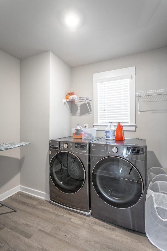 clothes washing area featuring washing machine and dryer and light hardwood / wood-style flooring