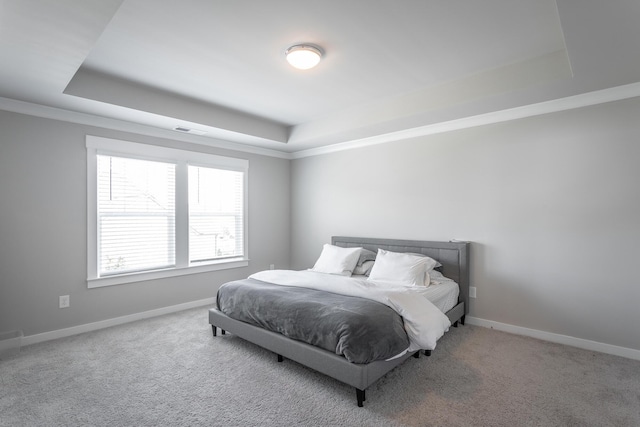 carpeted bedroom featuring ornamental molding and a tray ceiling