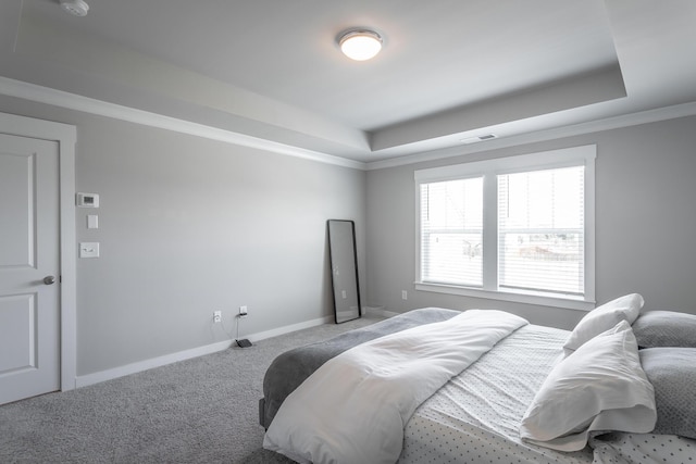 bedroom with ornamental molding, light colored carpet, and a tray ceiling