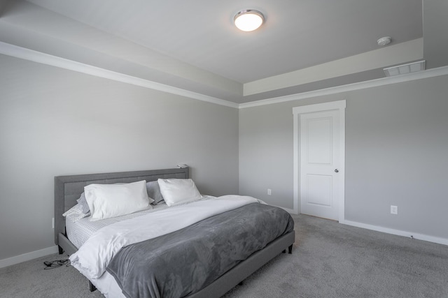 carpeted bedroom with ornamental molding and a tray ceiling