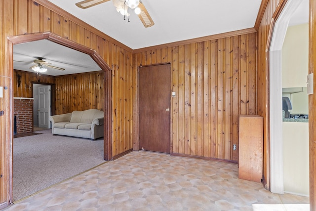 interior space with ceiling fan, light colored carpet, and wooden walls