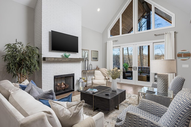 living area with high vaulted ceiling, recessed lighting, wood finished floors, french doors, and a brick fireplace