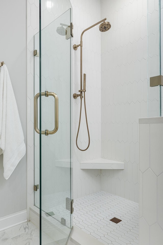 full bathroom with marble finish floor, a shower stall, and baseboards