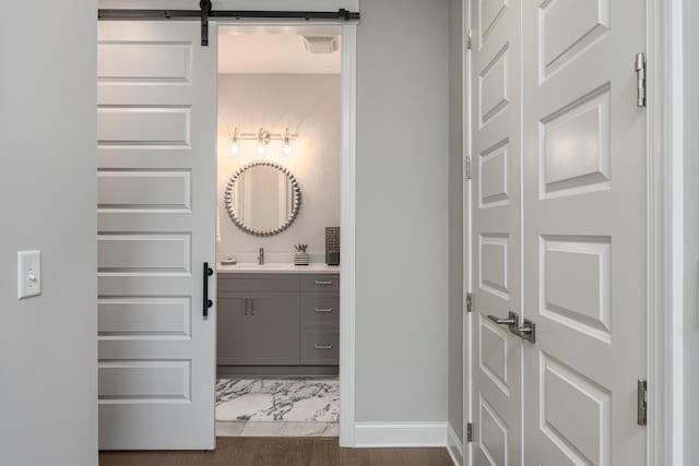 bathroom with visible vents, vanity, baseboards, and wood finished floors