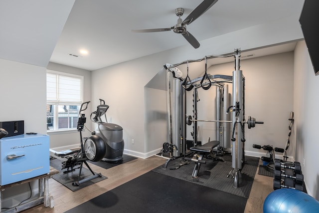 exercise area with a ceiling fan, baseboards, and wood finished floors