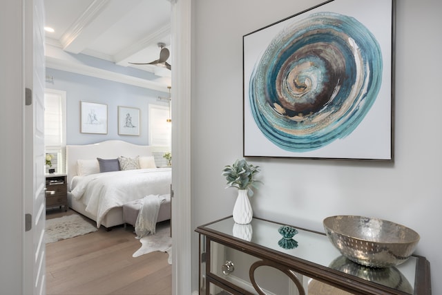 bedroom featuring ornamental molding, beam ceiling, and wood finished floors