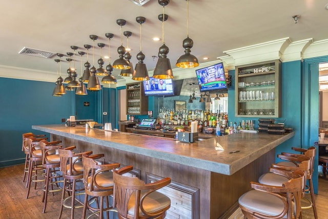 bar with a dry bar, visible vents, ornamental molding, wood finished floors, and pendant lighting